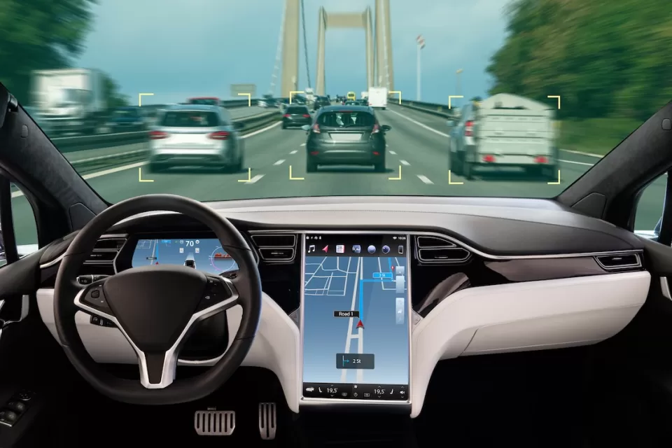 Interior of autonomous car with large map screen on road.